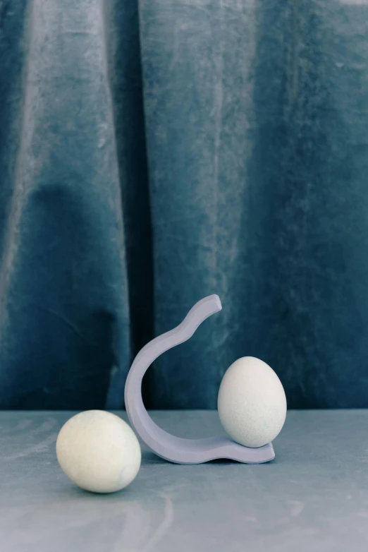 two eggs sitting next to each other on a table, an abstract sculpture, inspired by Isamu Noguchi, blue gray, winding horn, 2022 photograph, modelling