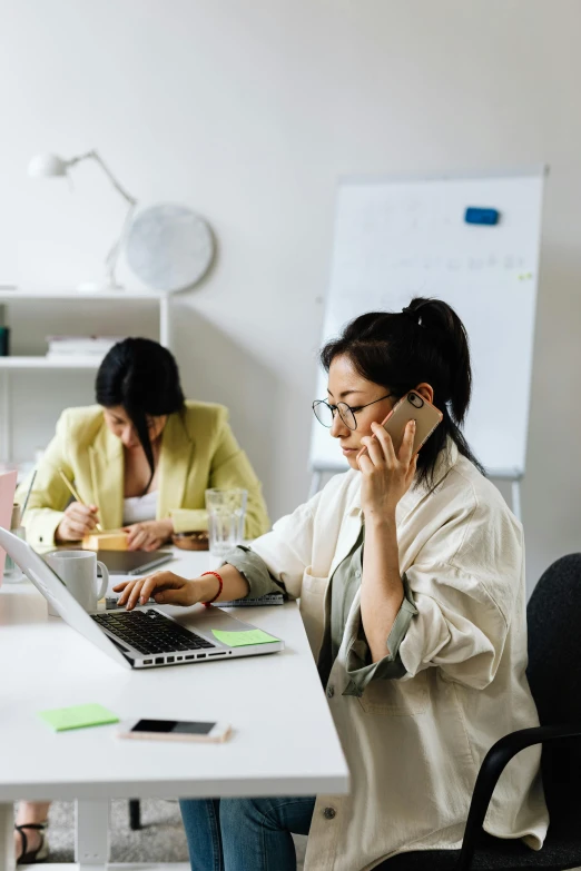 a woman sitting at a desk talking on a cell phone, by Jang Seung-eop, trending on pexels, in meeting together, laptops, slightly minimal, language