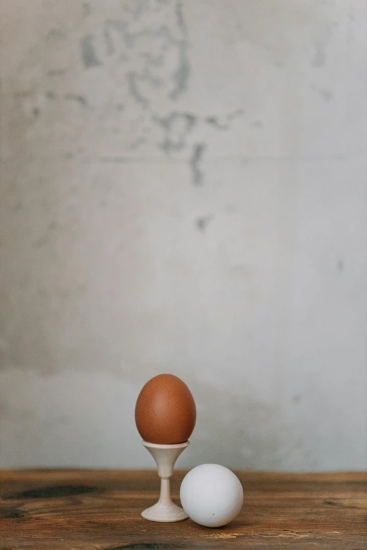 a couple of eggs sitting on top of a wooden table, by Jan Tengnagel, hyperrealism, on a marble pedestal, jeongseok lee, minimalist photorealist, brown