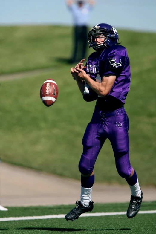 a man holding a football on top of a field, ((purple)), action sports photography, ap news photograph