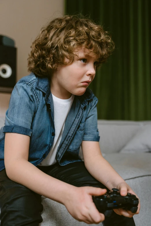 a young boy sitting on a couch holding a video game controller, an album cover, pexels, happening, tense look, wearing casual clothing, thumbnail, max dennison