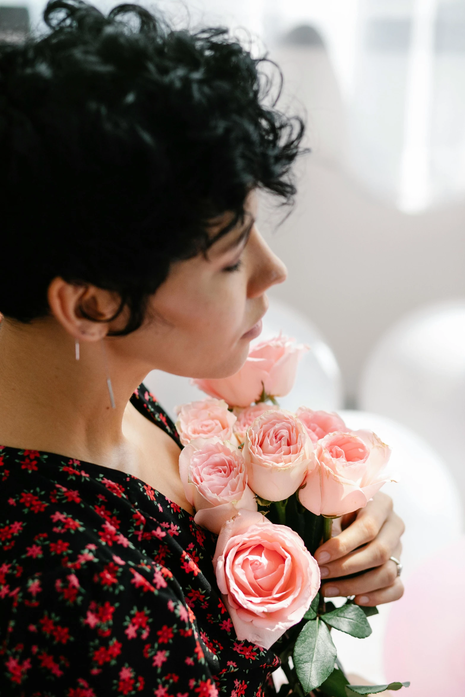 a woman holding a bunch of pink roses, an album cover, pexels contest winner, romanticism, sarah andersen, thoughtful expression, loving embrace, indoor picture