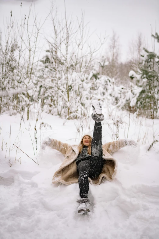 a woman laying in the snow with her arms in the air, pexels contest winner, land art, espoo, doing a sassy pose, low quality photo, minn