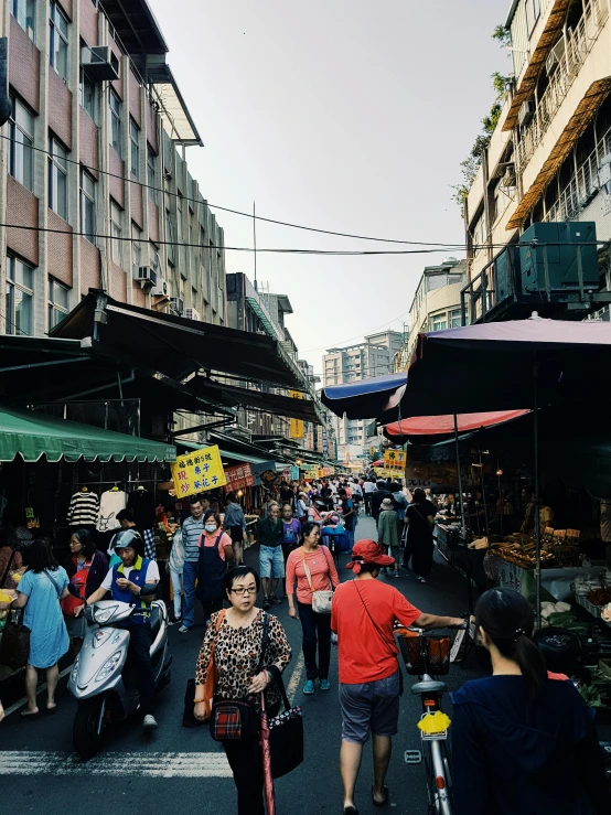 a group of people walking down a street next to tall buildings, wet market street, instagram picture, fresh food market people, conde nast traveler photo