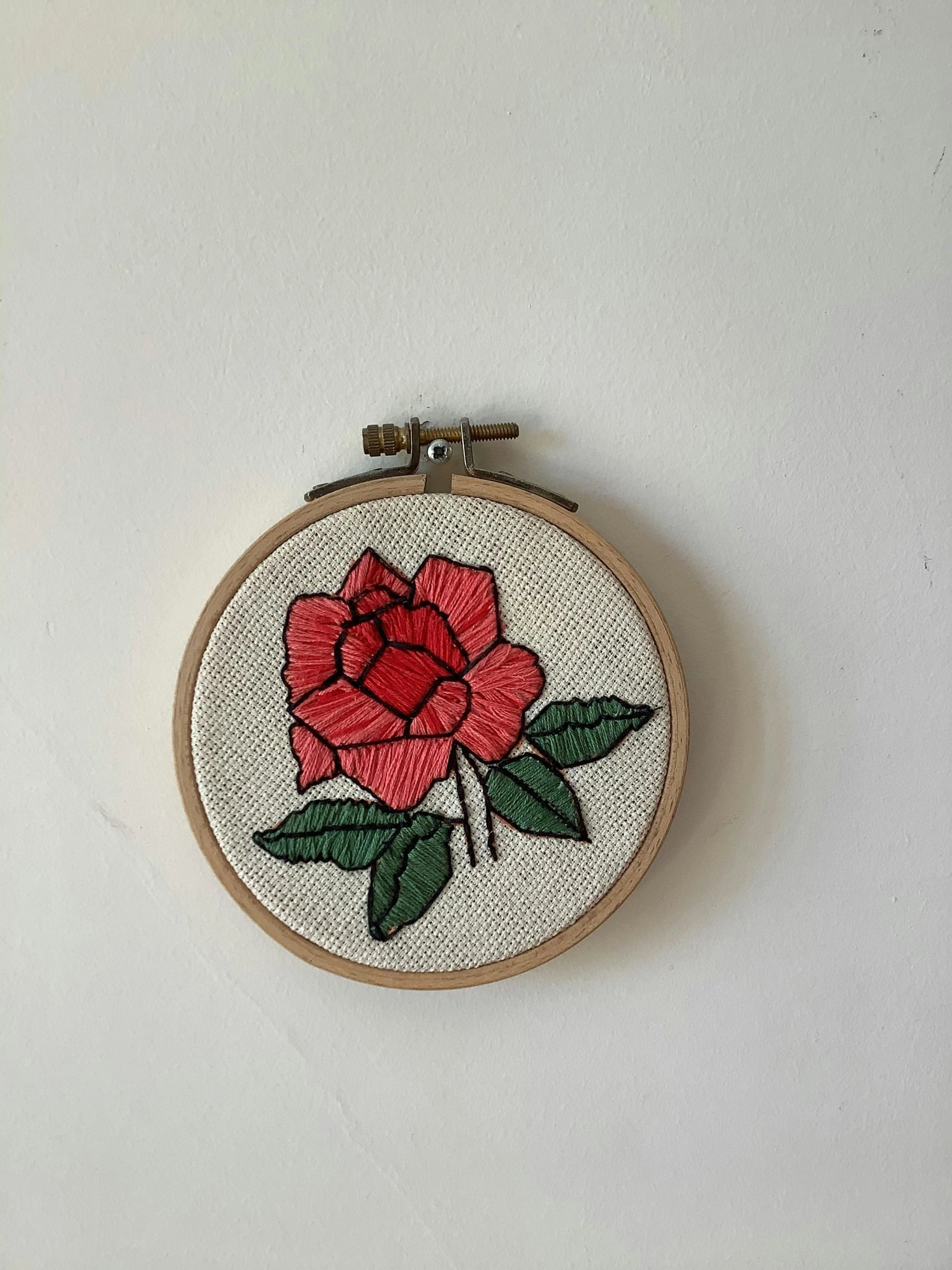 a close up of a embroidery on a wall, by Andrée Ruellan, red rose, simple aesthetic, hanging, retro style ”