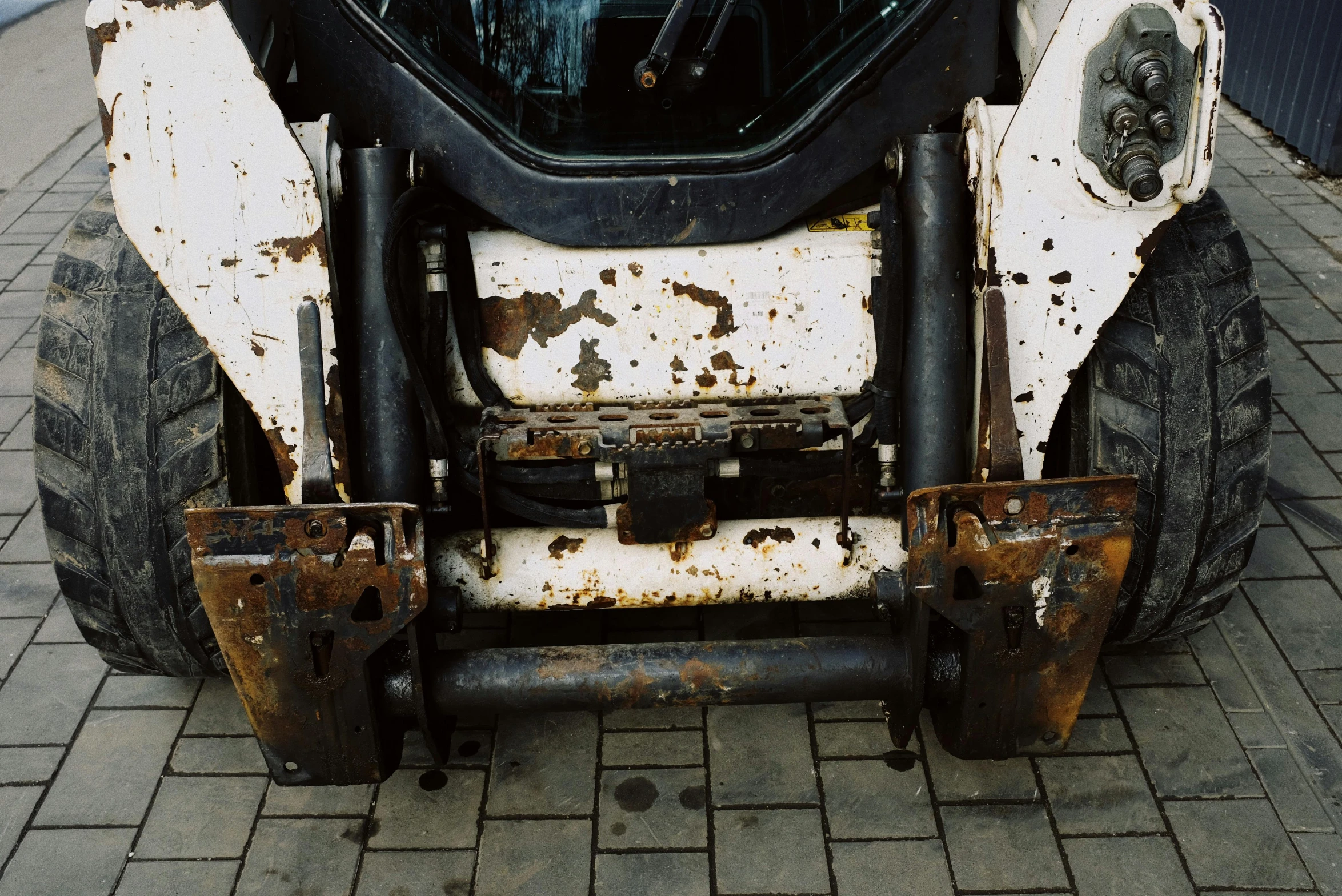 a close up of a tractor on a brick road, white with black spots, scrap metal, shot on hasselblad, heavy body modification