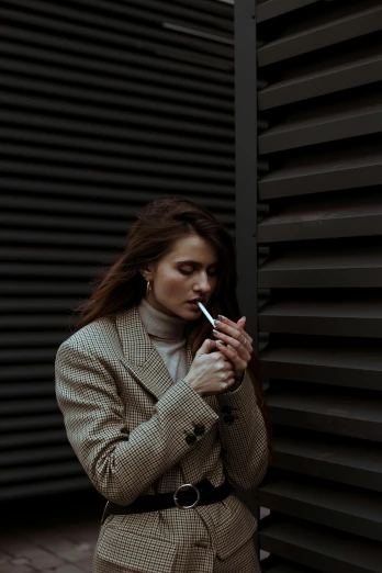 a woman in a suit smoking a cigarette, inspired by Elsa Bleda, trending on pexels, brown haired, wearing a sweater, ( 3 1, casual pose
