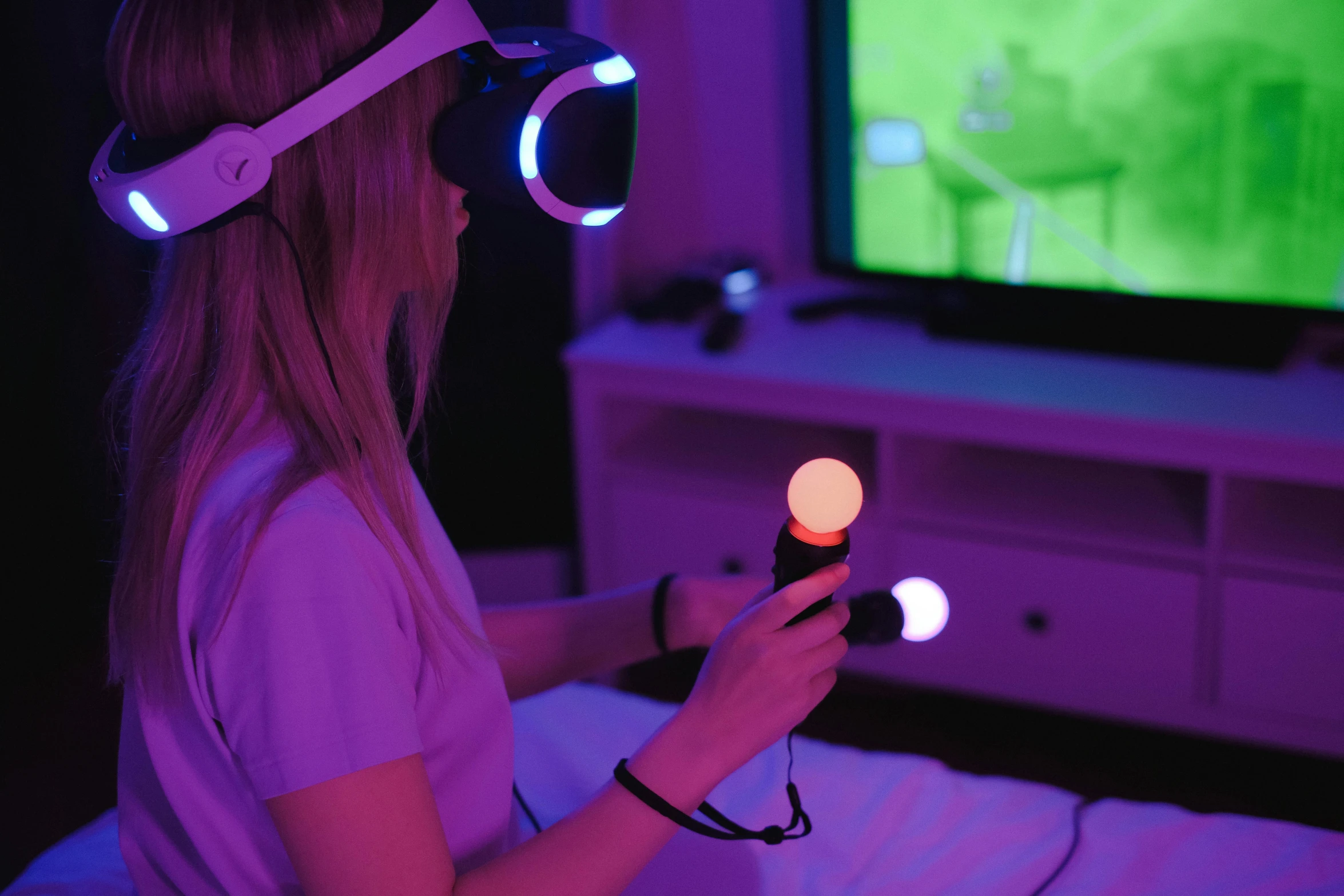 a woman sitting in front of a tv playing a video game, a hologram, inspired by Niko Henrichon, unsplash, interactive art, holding a glowing orb, brightly lit purple room, wearing a gaming headset, anaglyph lighting