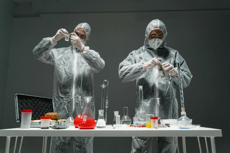 a couple of people that are standing in front of a table, shutterstock, process art, meth lab, tools for science research, dramatic product photography, wearing long silver robes