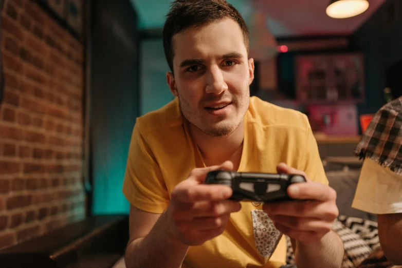 a man in a yellow shirt playing a video game, pexels, realism, mid-shot of a hunky, late night, playful smirk, instagram post