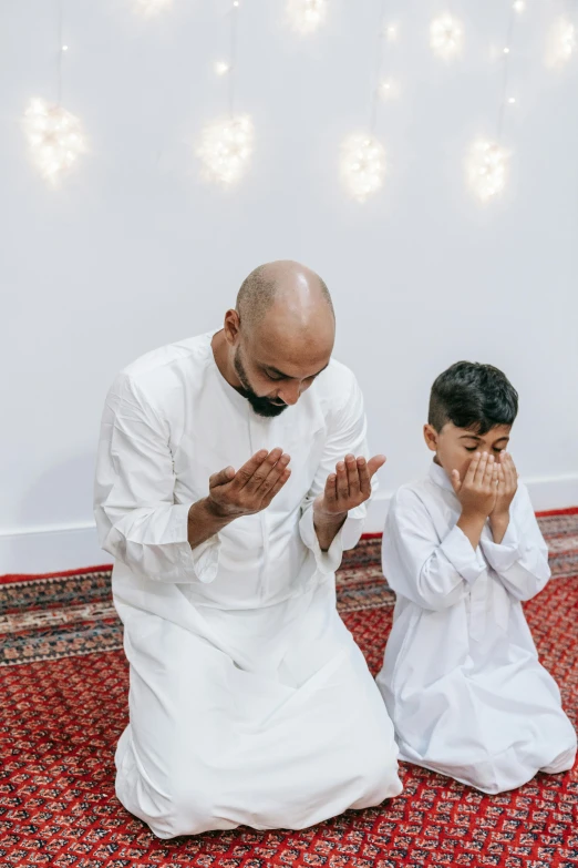 a man and a boy sitting on the floor praying, pexels contest winner, hurufiyya, giving a speech, sheikh, - 9, celebrating