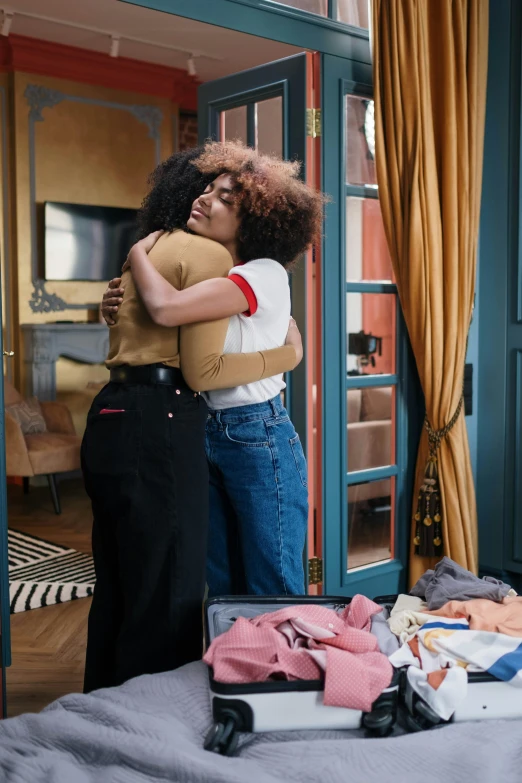 a couple of women standing next to each other on a bed, by Adélaïde Victoire Hall, pexels, happening, hugs, imaan hammam, in suitcase, grand finale