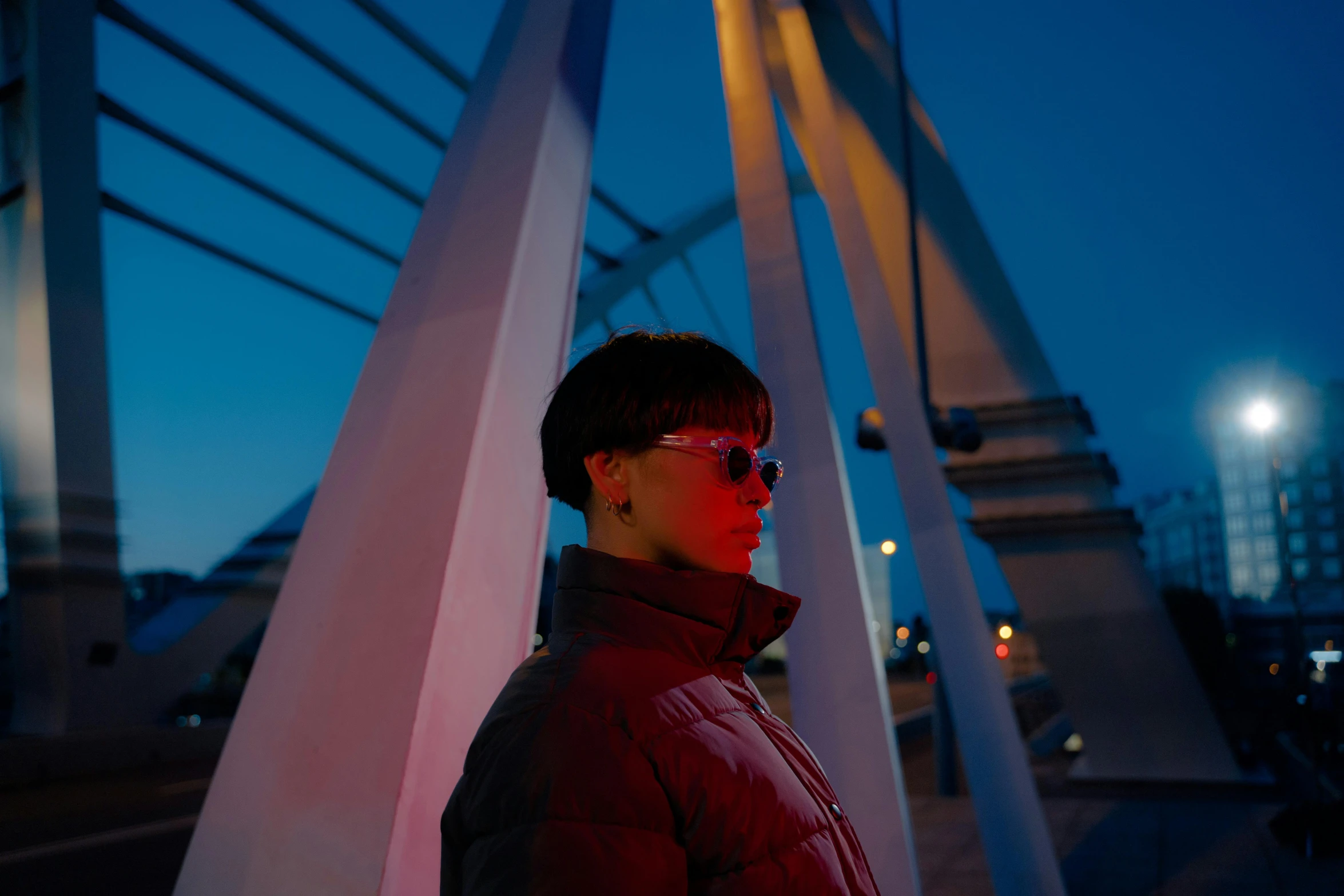 a man standing on top of a bridge at night, an album cover, inspired by Jean Malouel, pexels contest winner, left eye red stripe, woman with rose tinted glasses, wearing urban techwear, profile pic