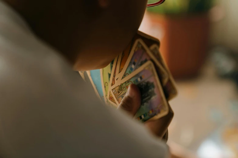 a close up of a person holding a bunch of cards, by Daniel Lieske, pexels contest winner, tabletop gaming, natural morning light, childish, multi colored