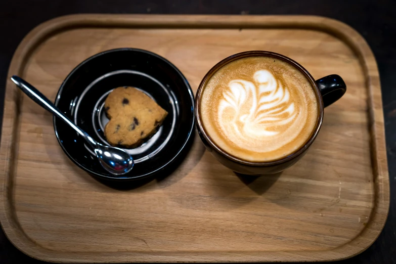 two cups of coffee and a cookie on a tray, by Matthias Stom, unsplash, japanese akihabara cafe, a wooden, on black background, milk and mocha style