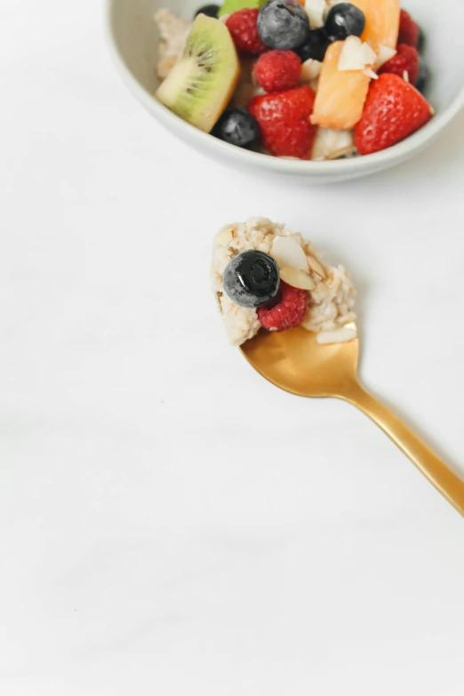 a close up of a bowl of food with a spoon, by Andries Stock, berries, white marble and gold, hero shot, premium