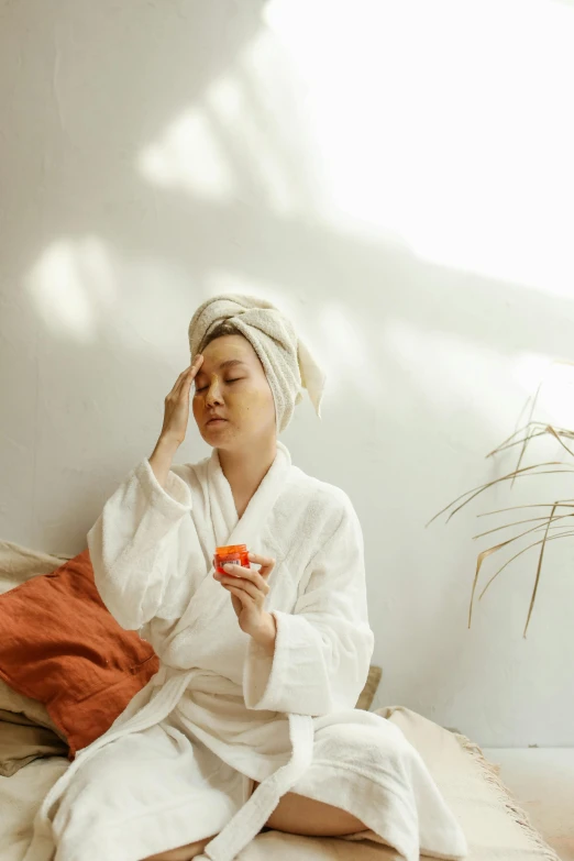 a woman sitting on a bed with a towel on her head, trending on pexels, renaissance, asian sun, on a white table, manuka, gif