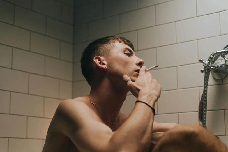a man sitting in a bathroom brushing his teeth, by Jessie Alexandra Dick, trending on pexels, hyperrealism, lips on cigarette, young man with short, shaved, profile image