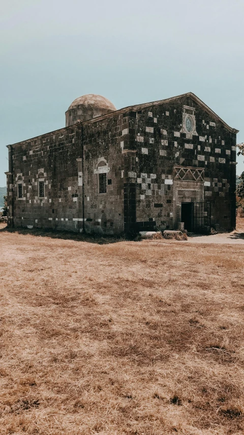 a large stone building sitting on top of a dirt field, unsplash contest winner, romanesque, orthodox, on the coast, low quality photo, italy