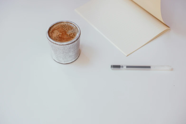 a cup of coffee and a pen on a table, postminimalism, detailed product image, white-space-surrounding, grey, full product shot