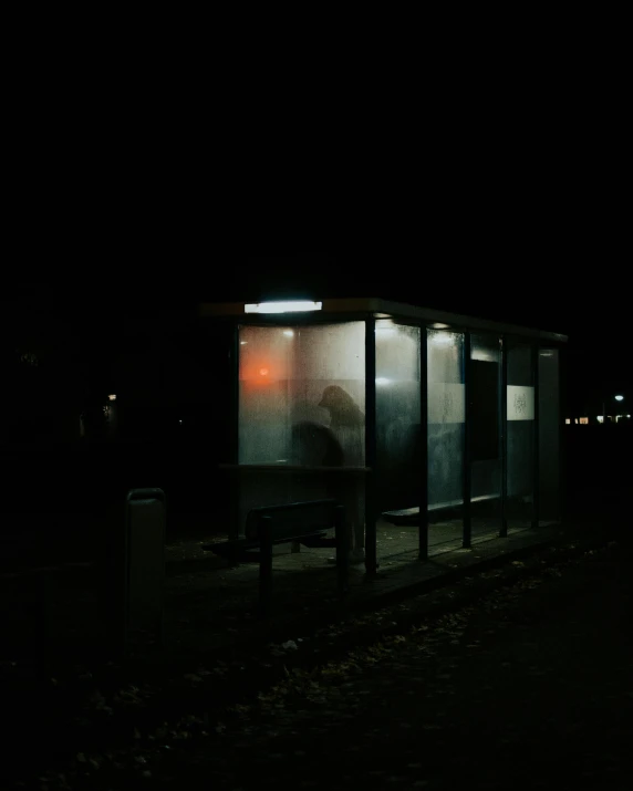 a person sitting at a bus stop at night, an album cover, by Attila Meszlenyi, unsplash, very dark and abandoned, ignant, station, 3 am