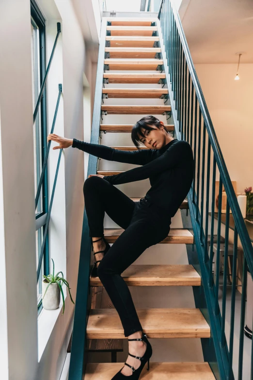 a woman sitting on a set of stairs, by Nina Hamnett, pexels contest winner, black spandex, in a japanese apartment, wearing a track suit, designed for cozy aesthetics!