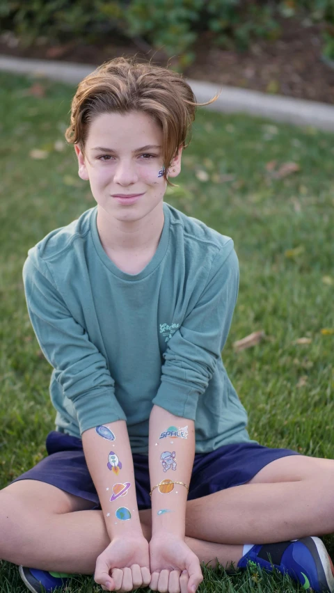 a young boy sitting on top of a lush green field, a tattoo, by Samuel Scott, pexels, temporary tattoo, day - glow facepaint, pale bluish skin, modeled