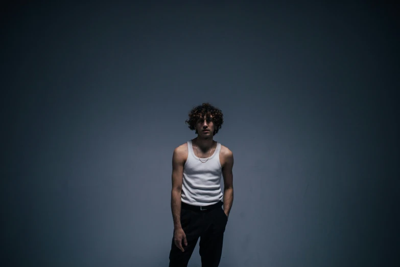 a man standing on a skateboard in a dark room, an album cover, pexels contest winner, antipodeans, robert sheehan, in a white tank top singing, portrait image, pensive lonely