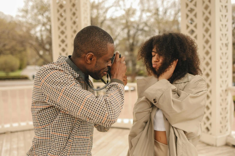 a man taking a picture of a woman with a camera, pexels contest winner, a black man with long curly hair, comforting, high detailed photography cape, male and female