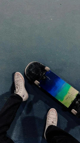 a person standing next to a skateboard on the ground, high above the ground, low quality photo, instagram post, black blue green