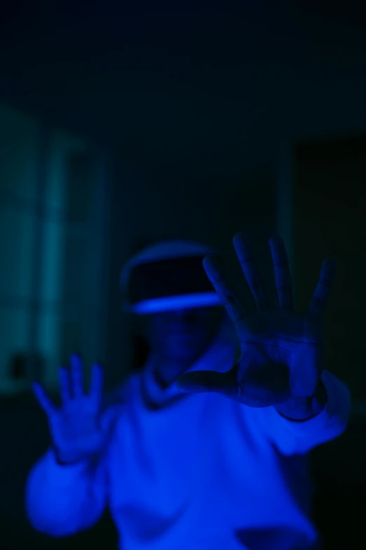 a person wearing a virtual reality headset in a dark room, a hologram, pexels, waving hands, dramatic white and blue lighting, taken with sony alpha 9, video game avatar