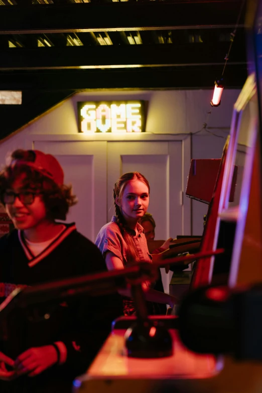 a group of people playing video games in a room, arcade cabinet, finn wolfhard, slide show, lights on