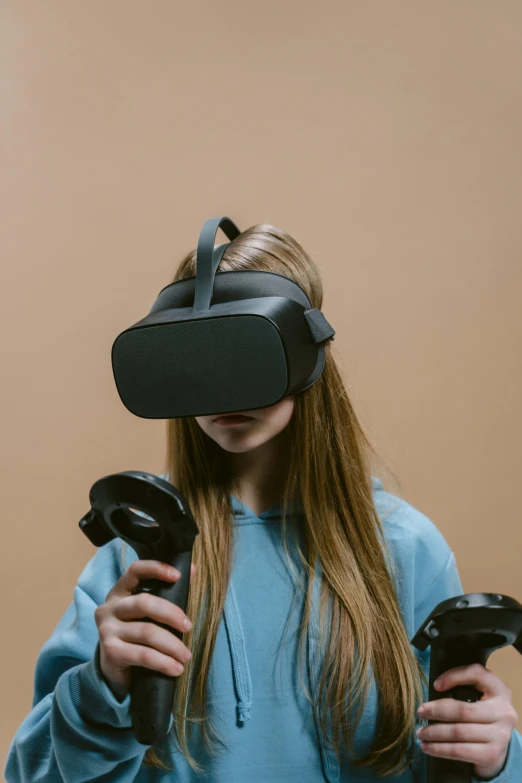 a girl in a blue hoodie holding two video game controllers, hypermodernism, oculus quest 2, dark. no text, inspect in inventory image