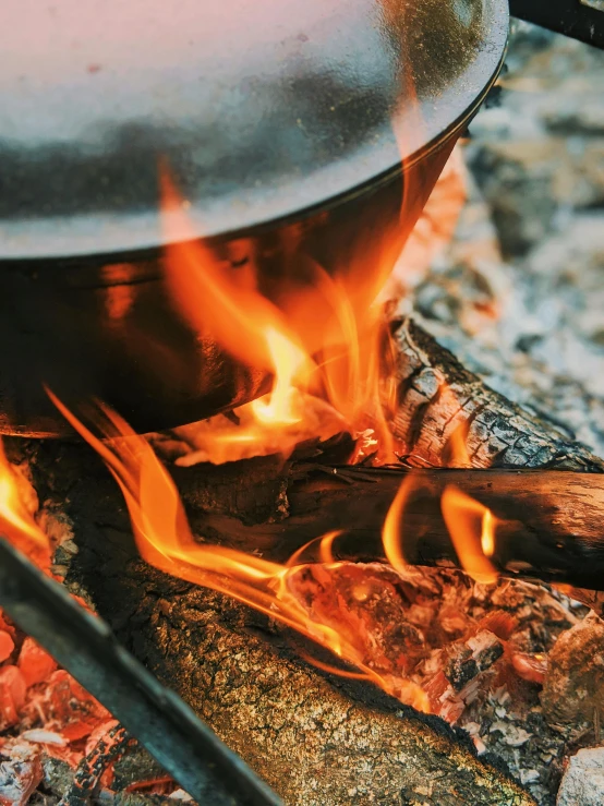 a pot sitting on top of an open fire, up close, fire from mouth, multiple stories, cooking it up