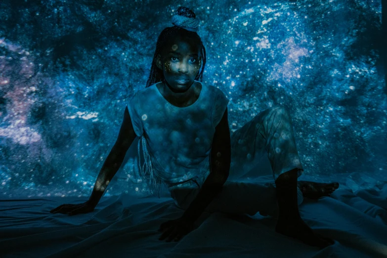 a woman sitting on top of a bed next to a cat, an album cover, pexels contest winner, afrofuturism, blue bioluminescence, man in dark blue full body suit, teamlab, portrait photo of a backdrop