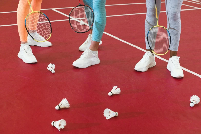 a group of women standing on top of a tennis court holding racquets, by Nina Hamnett, trending on pexels, hyperrealism, fibres trial on the floor, red and white color scheme, badminton, close-up on legs