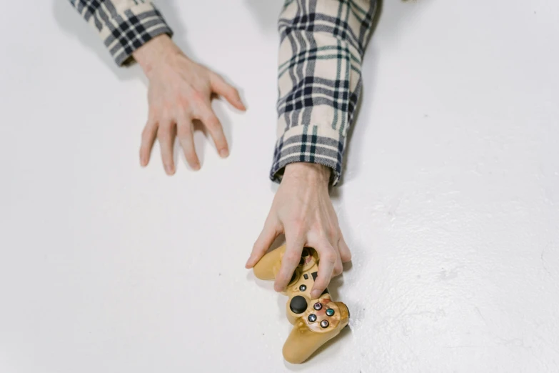 a close up of a person holding a video game controller, inspired by Sarah Lucas, on a white table, beaten, on a checkered floor, ignant