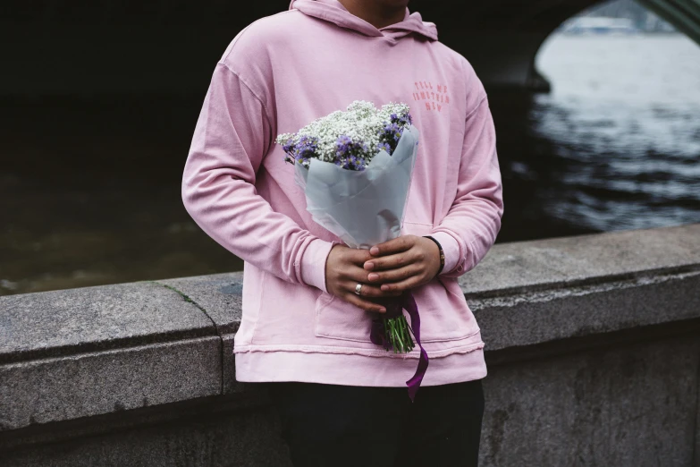 a man in a pink hoodie holding a bunch of flowers, inspired by Elsa Bleda, pexels contest winner, aestheticism, wearing sweatshirt, lilac, street wear, understated