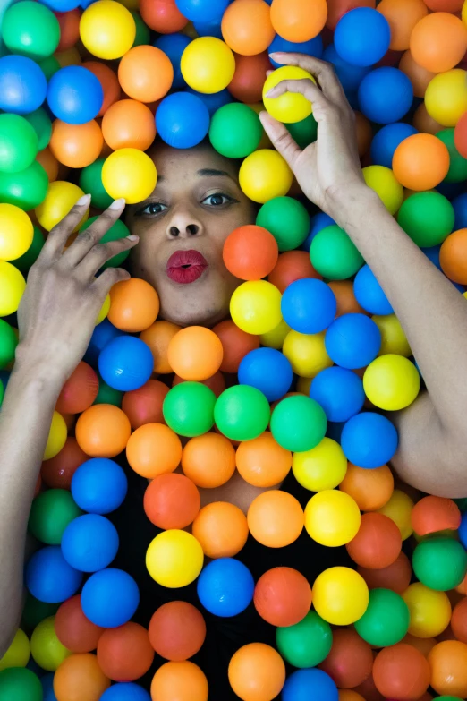 a woman in a ball pit with lots of colorful balls, lips, ( ( dark skin ) ), square, shot with sony alpha