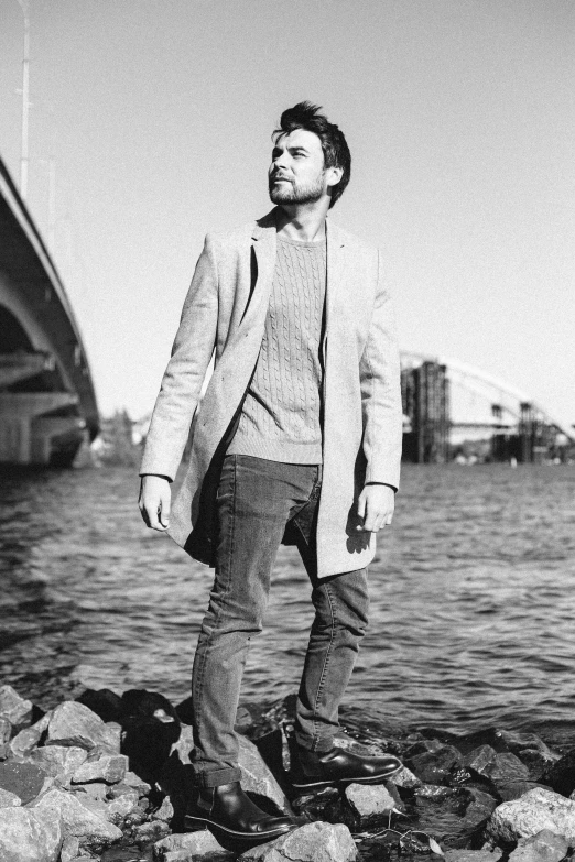 a man standing next to a body of water, a black and white photo, sebastian stan, street photo, profile picture 1024px, harbour