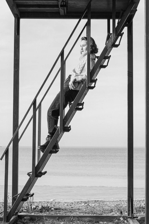 a black and white photo of a man sitting on a stair, a black and white photo, inspired by Louis Stettner, surrealism, at the seaside, ( ( photograph ) ), robert plant, square