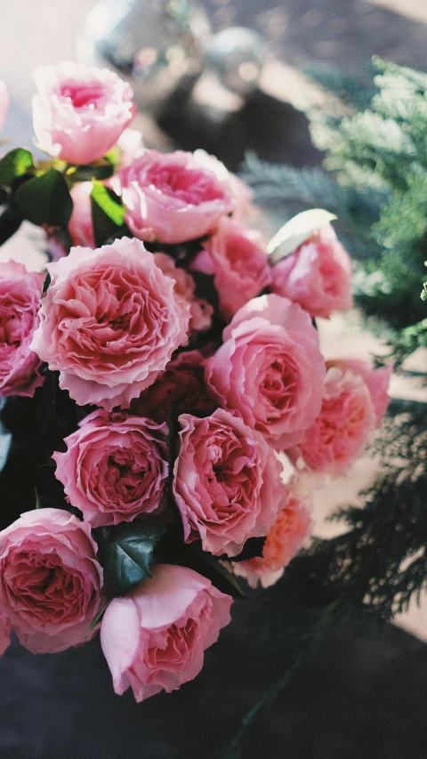 a bouquet of pink roses sitting on top of a table, by Rachel Reckitt, unsplash, lush flowery outdoors, loosely cropped, analogue photo, no cropping