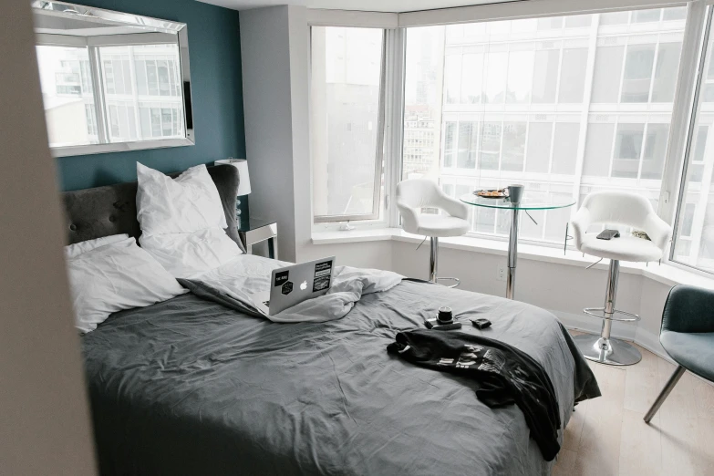 a bed sitting in a bedroom next to a window, unsplash contest winner, happening, grey and blue theme, busy room, luxury condo interior, snapchat photo