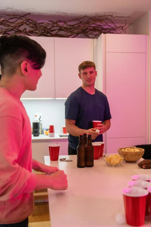 a group of people standing around a kitchen counter, by John Luke, happening, bisexual lighting, having a snack, profile image, pink