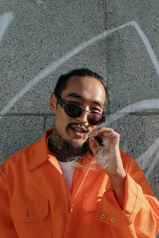 a man in an orange shirt talking on a cell phone, inspired by Zhu Da, trending on pexels, visual art, post malone, half asian, he wears an eyepatch, smoke all around