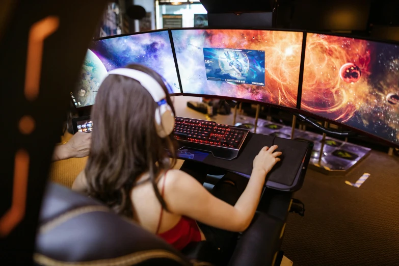 a woman sitting at a desk in front of three computer monitors, by Julia Pishtar, pexels, gaming toilet, panoramic view of girl, high angle shot, queen of the galaxy