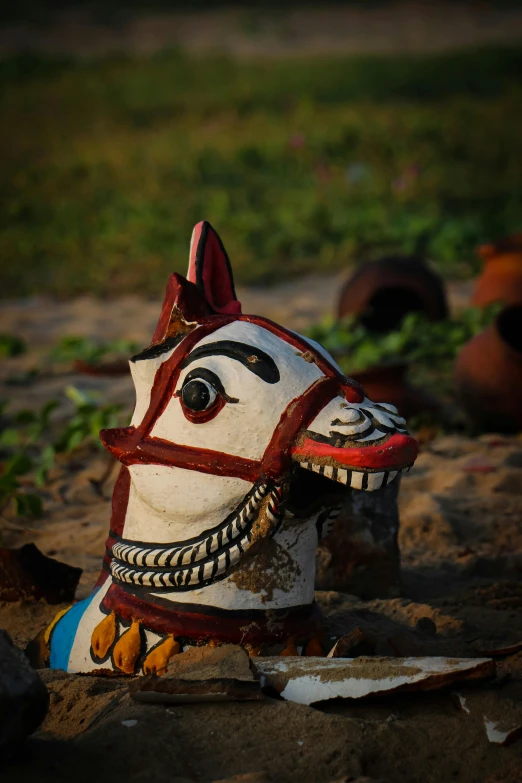 a close up of a toy horse on the ground, inspired by Steve McCurry, folk art, wooden jagannath face, sundown, tribal masks, sri lanka