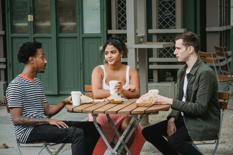 a group of people sitting around a wooden table, tessa thompson, aussie baristas, sitting on a park bench, felix kelly