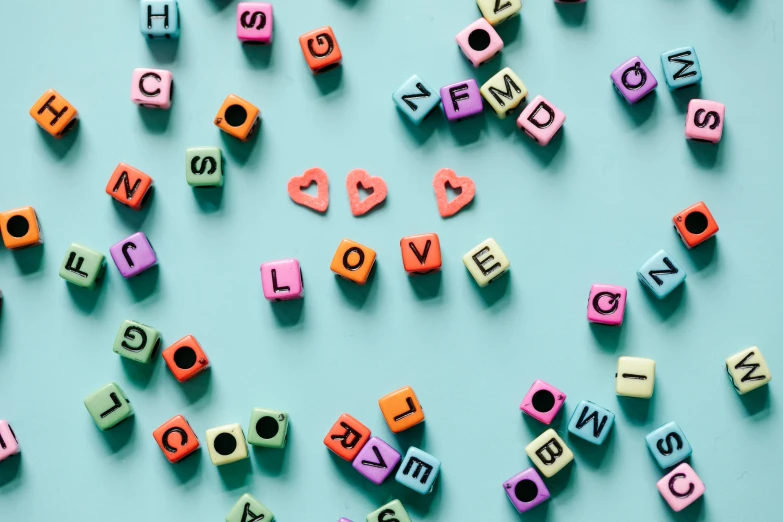 colorful wooden letters spelling i love you on a blue background, trending on pexels, cubes on table, pastel goth aesthetic, beads, connected to heart machines