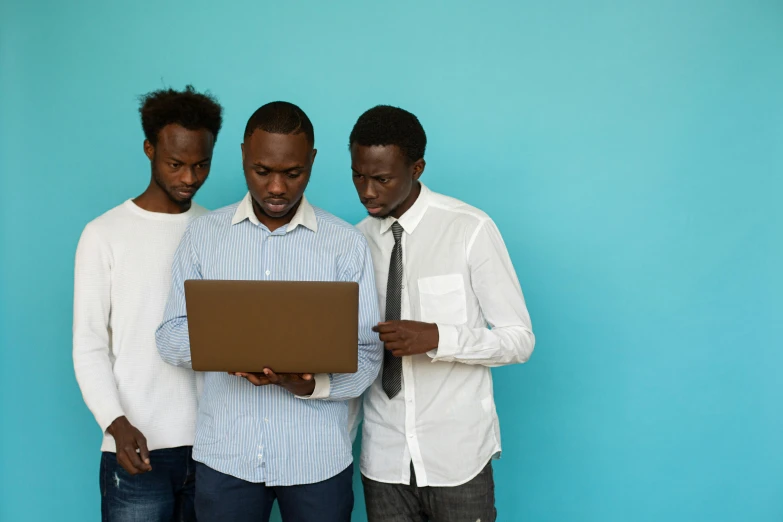 three men standing next to each other looking at a laptop, trending on unsplash, ( brown skin ), with a blue background, teaching, plain background